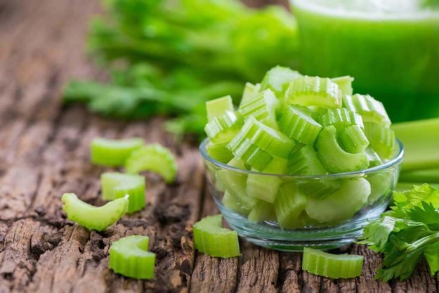 fresh sliced green celery in glass on wood background