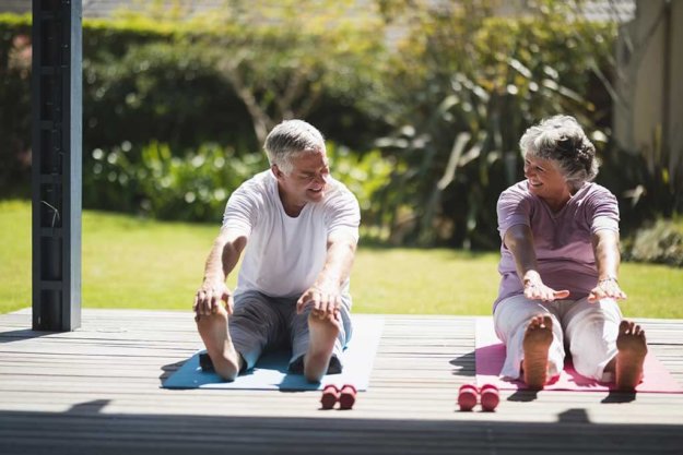 senior couple exercising together on mat at porch senior couple exercising together on mat at porch