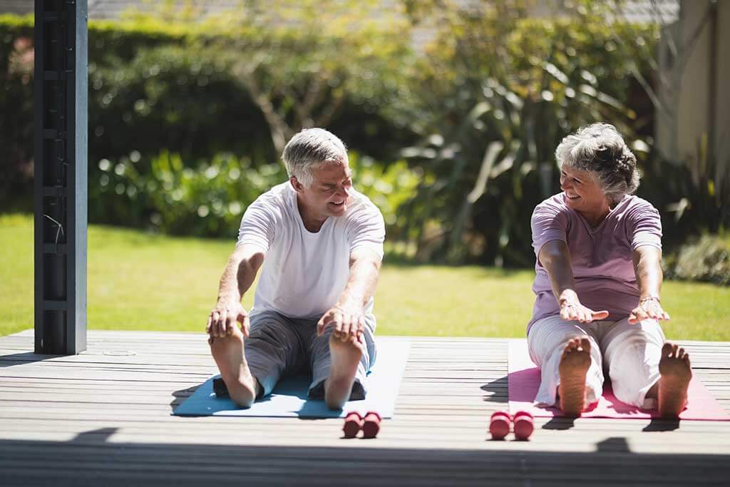 senior couple exercising together on mat at porch