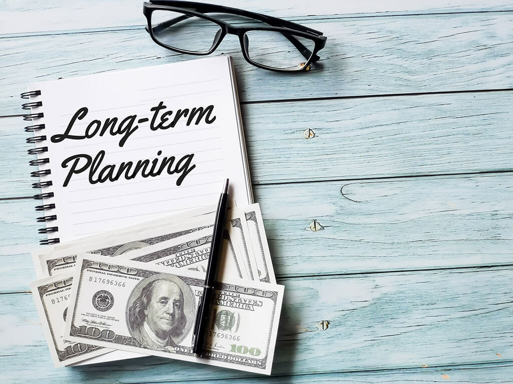 business and finance concept phrase long term planning written on note book with fake money