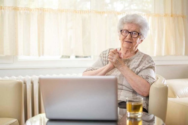 emotional senior woman having video call with grandchildren via laptop
