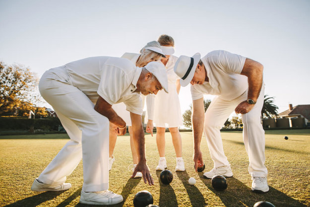 group of senior men and women playing boules in a lawn group of senior men and women playing boules in a lawn