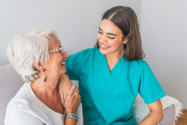 nurse talking with senior woman sitting in chair on home visit