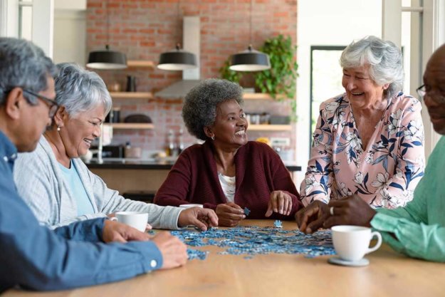group of diverse senior male and female friends doing puzzles at home group of diverse senior male and female friends doing puzzles at home