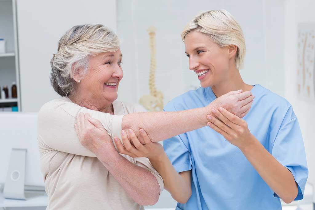 happy nurse assisting patient in raising arm