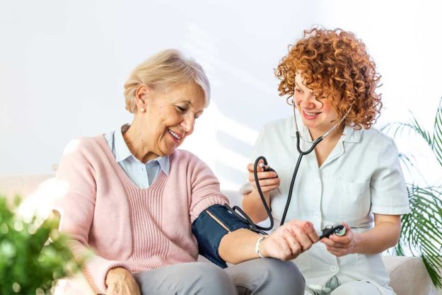 happy nurse measuring blood pressure of a senior woman happy nurse measuring blood pressure of a senior woman
