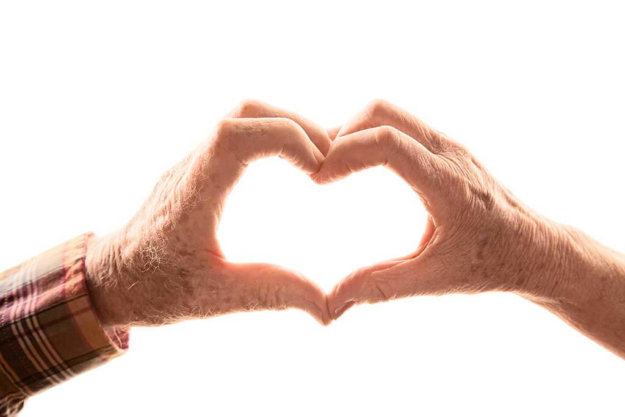 senior couple forming heart with hands