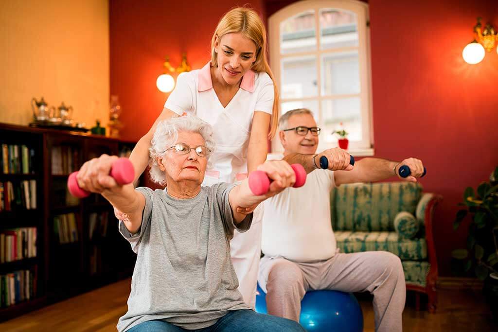 senior couple with dumbbells in rehab with a physiotherapist