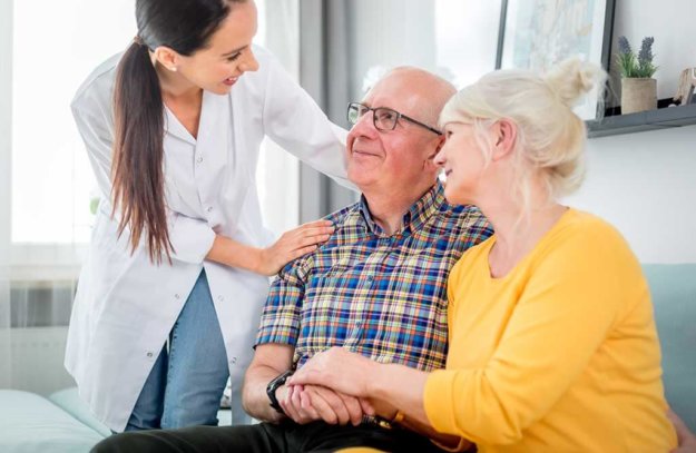 smiling nurse talking with senior couple during home visit smiling nurse talking with senior couple during home visit