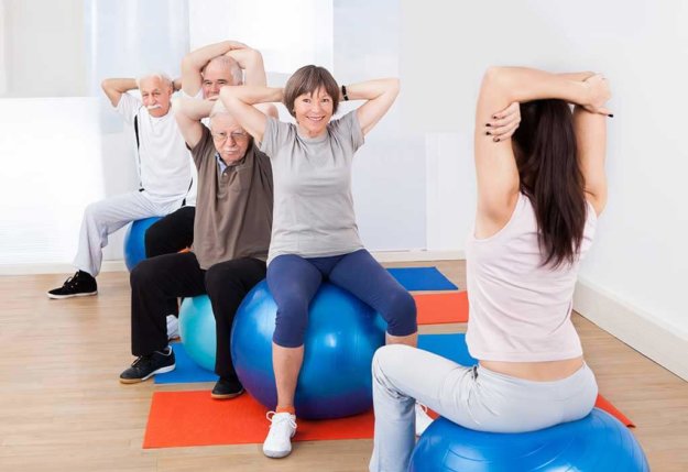 trainer training customers stretching on fitness balls
