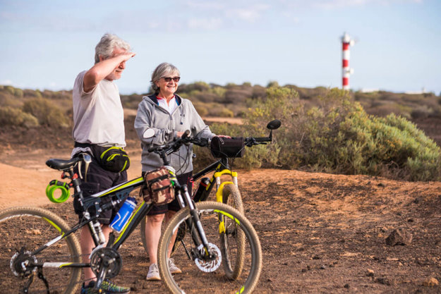 couple of beautiful caucasian active adult senior enjoy mountain bike