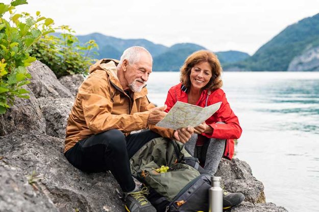 a senior pensioner couple hiking by lake in nature using map