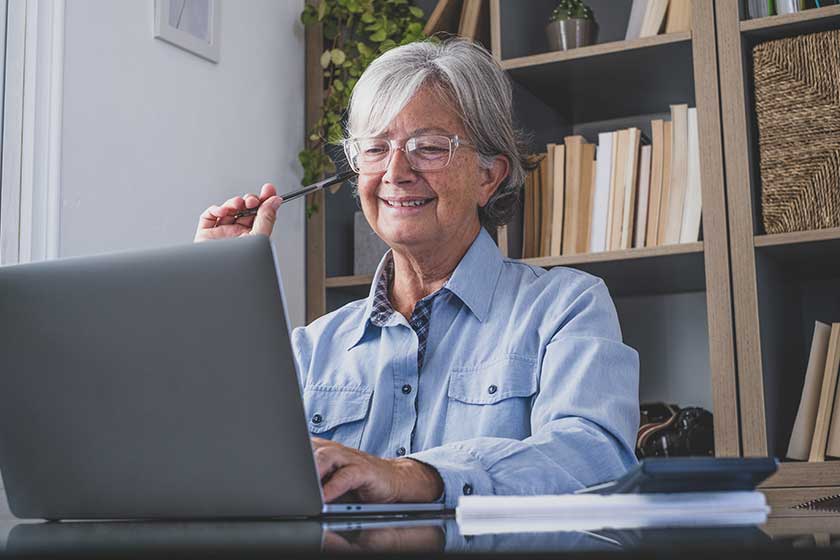 happy old caucasian businesswoman smiling working online watching webinar podcast on laptop