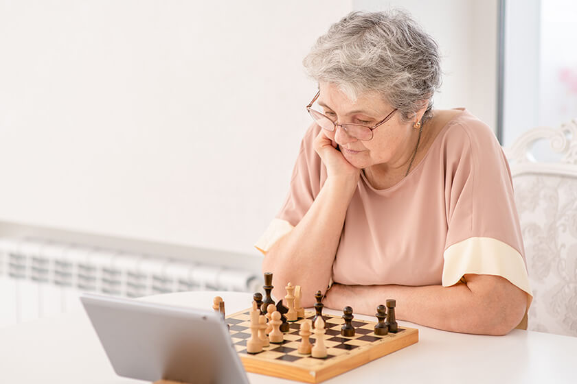 pensive senior woman uses tablet computer to play chess pensive senior woman uses tablet computer to play chess