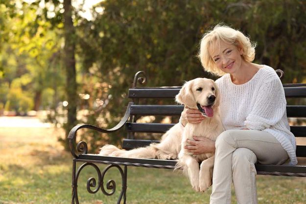 senior woman sitting on bench with dog