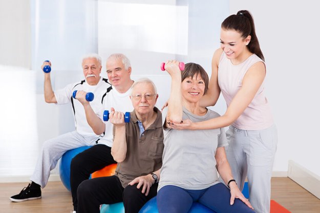 trainer assisting senior people at healthclub