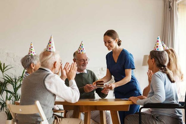 young nurse bringing birthday cake with candle for senior man young nurse bringing birthday cake with candle for senior man