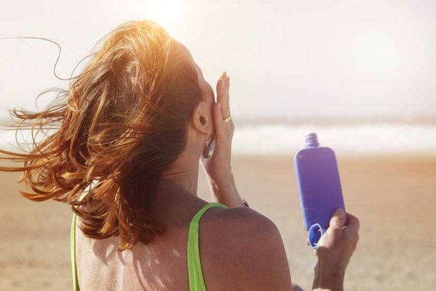 femme senior s enduisant de creme solaire a la plage femme senior s enduisant de creme solaire a la plage