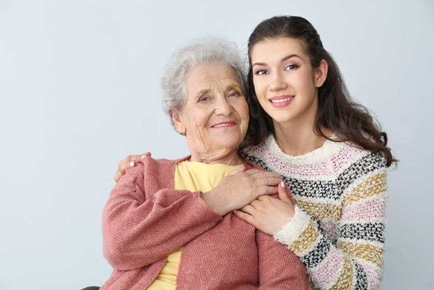 happy woman with grandmother on grey background