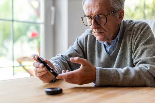 mature man checking blood sugar level with glucometer mature man checking blood sugar level with glucometer