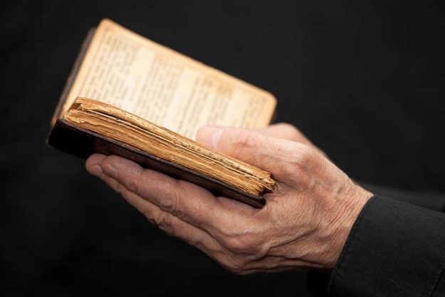 hands of an old man holding a book