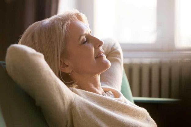 happy lazy old woman relaxing meditating leaning on comfortable sofa