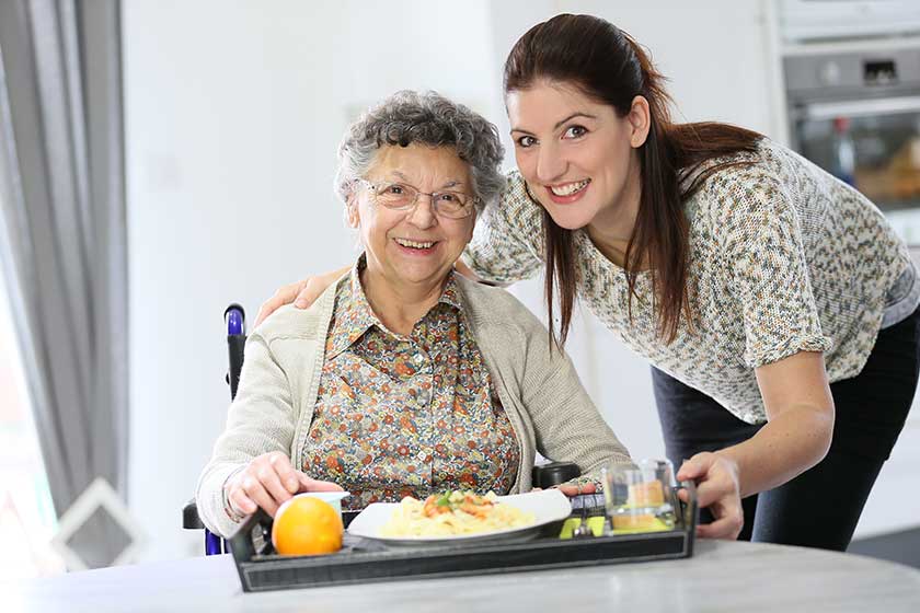 homecarer preparing lunch for elderly woman
