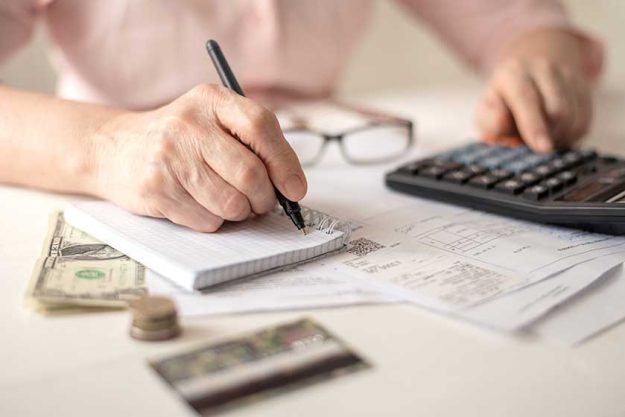 pension calculation concept old hands counting finances on a home calculator