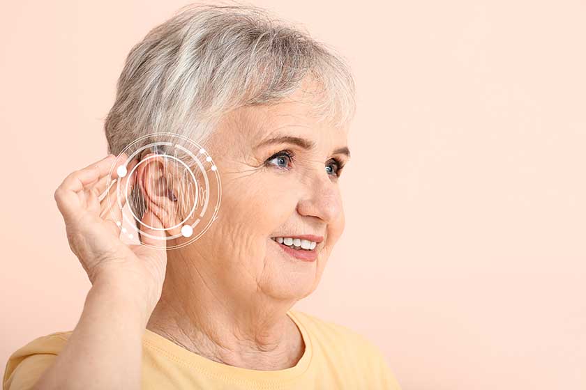 senior woman with hearing aid on color background