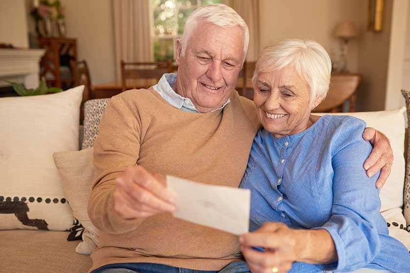 smiling senior couple looking at old photos together at home
