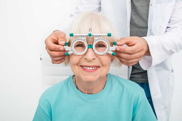 smiling senior woman wearing optometrist trial frame at ophthalmology clinic