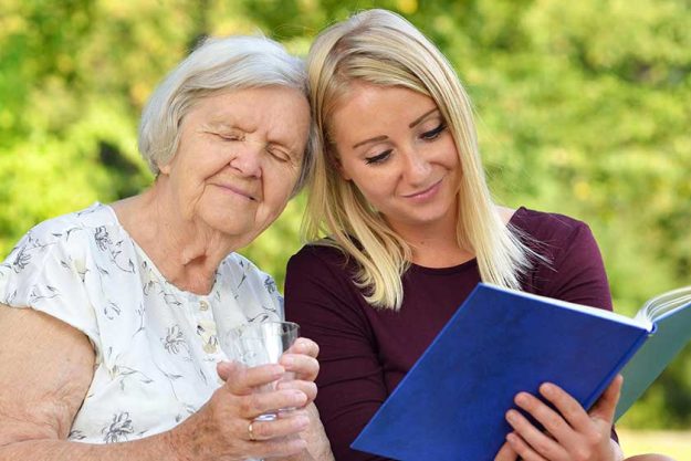 young woman reading a book elderly woman in the park young woman reading a book elderly woman in the park