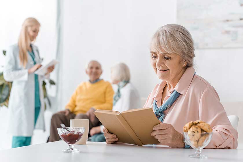 senior woman reading book while female doctor examining people