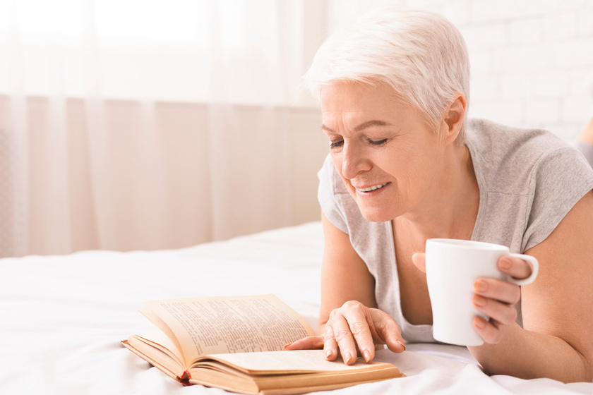 calm senior lady enjoying favorite book and hot tea calm senior lady enjoying favorite book and hot tea