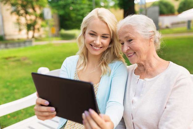 daughter with tablet pc and senior mother at park