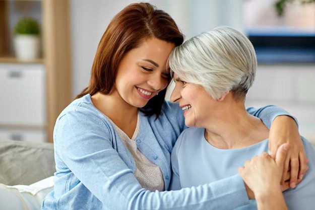 happy smiling senior mother with adult daughter hugging at home