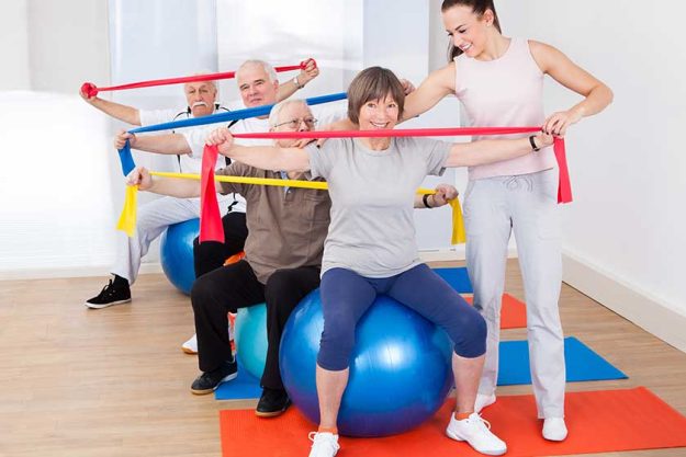 trainer assisting senior people at gym