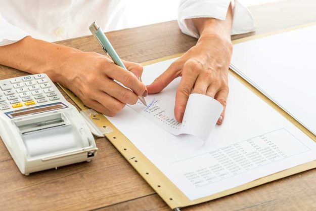 female accountant calculating and reviewing numbers on a receipt female accountant calculating and reviewing numbers on a receipt