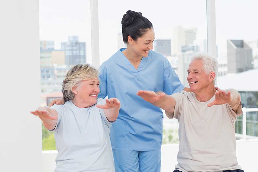female trainer assisting senior couple to exercise