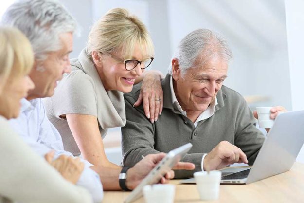 group of retired senior people using laptop and tablet