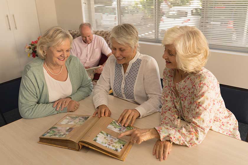 group of senior women looking at photo album at nursing home group of senior women looking at photo album at nursing home