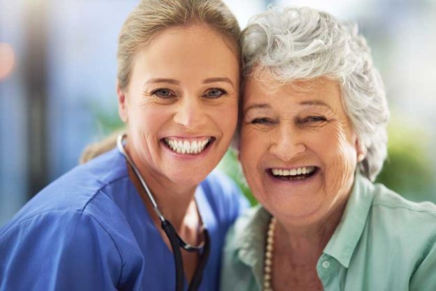 portrait of a smiling nurse with her senior patient in a hospital