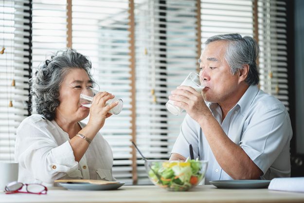 smiling asian senior man and woman drinking glasses of milk smiling asian senior man and woman drinking glasses of milk