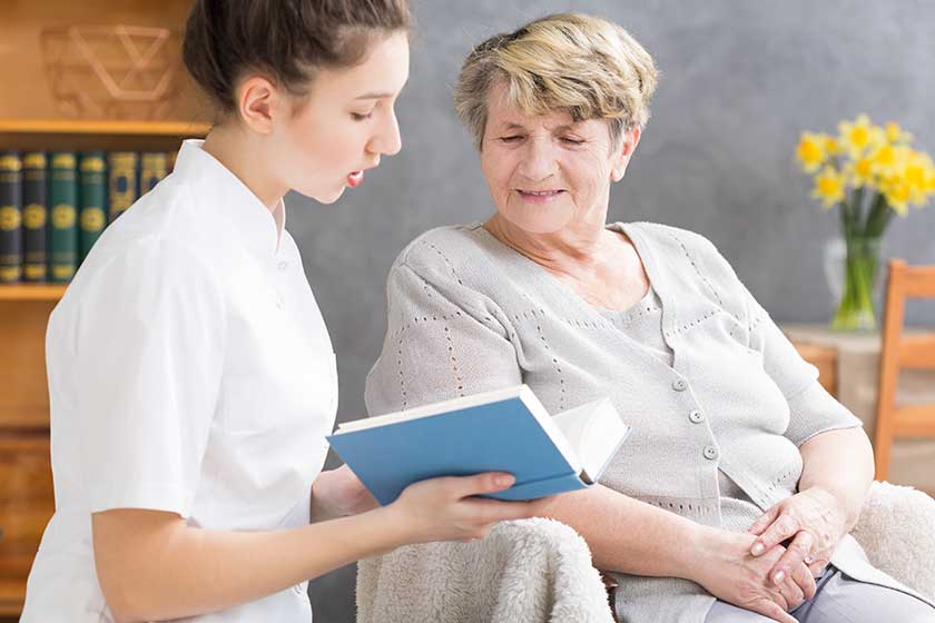 caregiver reading to senior lady