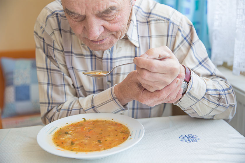 elderly man with parkinsons disease holds spoon in both hands elderly man with parkinsons disease holds spoon in both hands