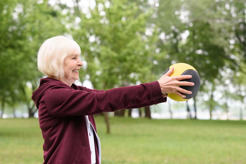 elderly woman exercising medicine ball