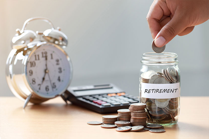 hand putting coins in glass jar with calculator and alarm clock