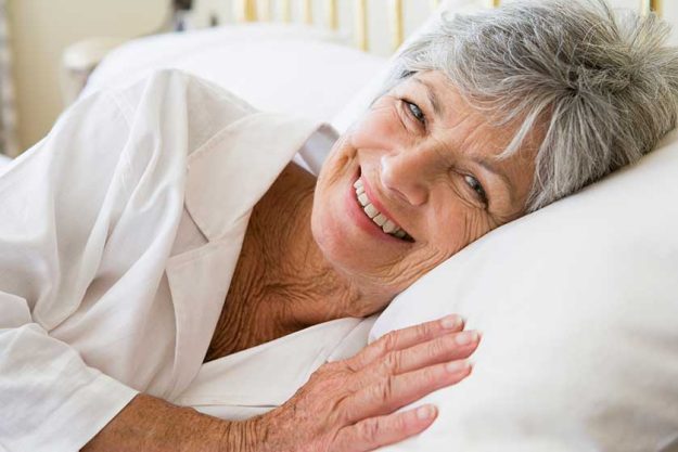 happy senior woman in bed at home looking at camera happy senior woman in bed at home looking at camera