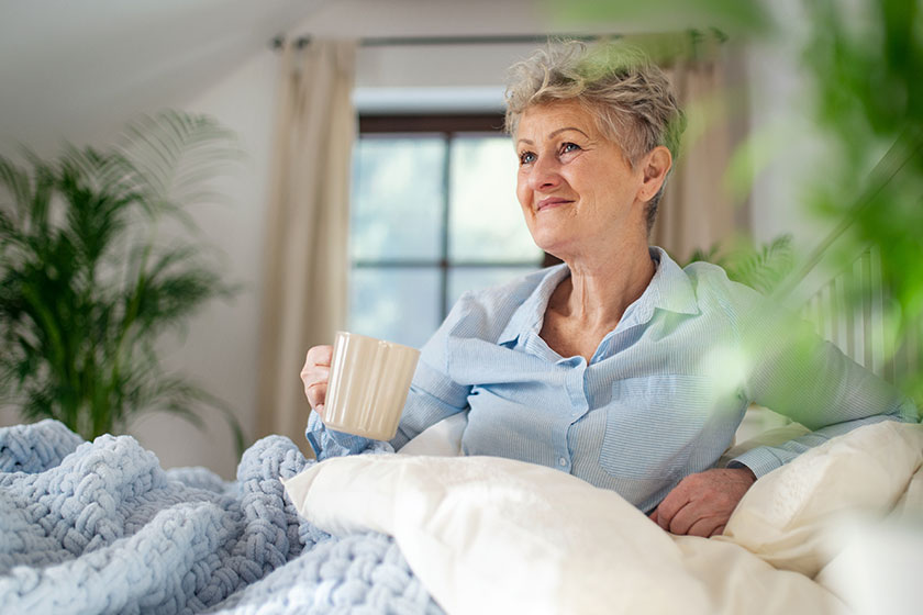 happy senior woman with a hot drink in bed happy senior woman with a hot drink in bed