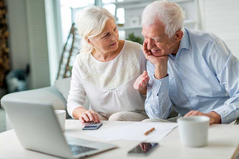 older couple reading papers together on sofa
